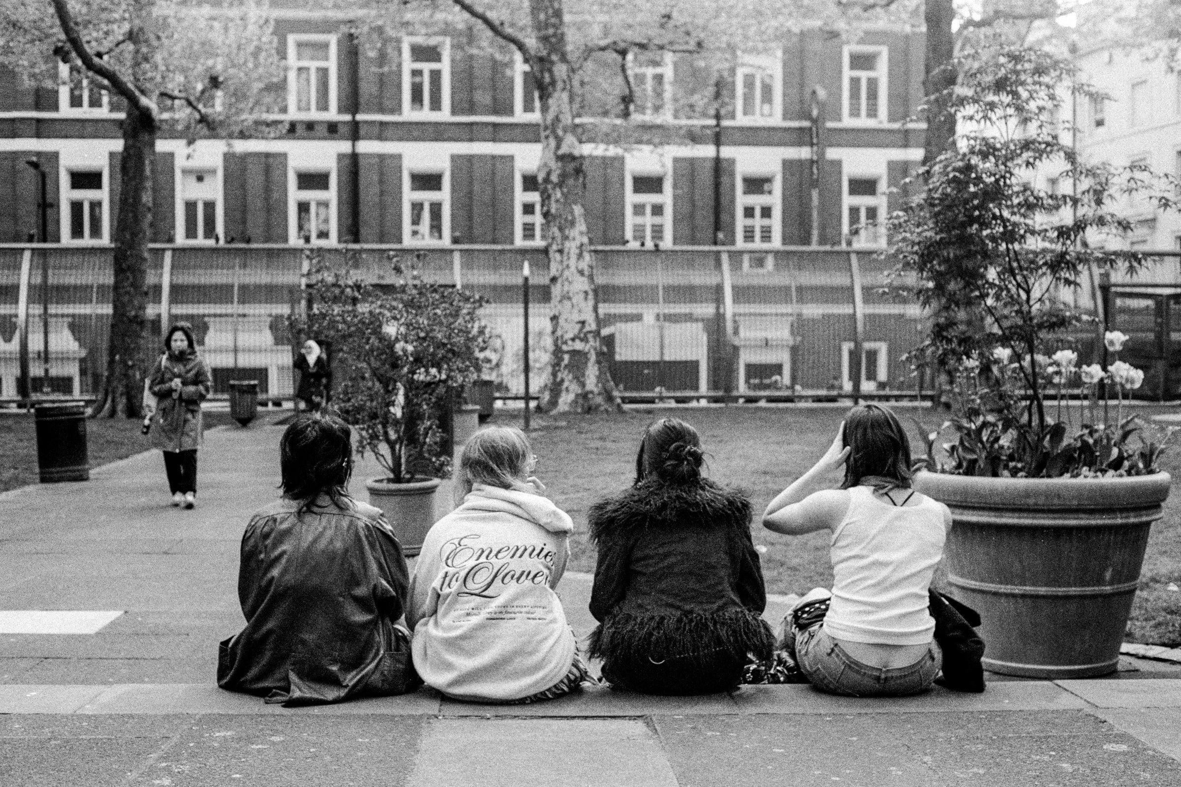Four women sit with their backs to the viewer in a London courtyard.